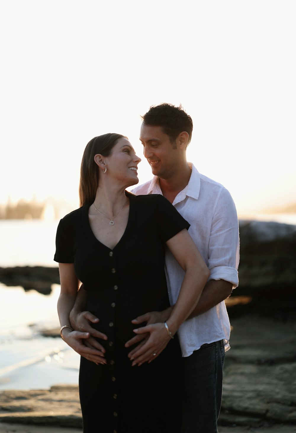 a man and woman standing next to each other on a beach