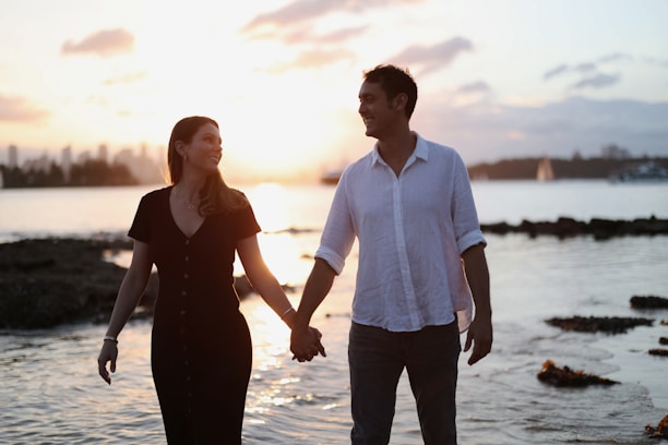 A couple walking hand-in-hand along a golden sunset beach, radiating genuine happiness.