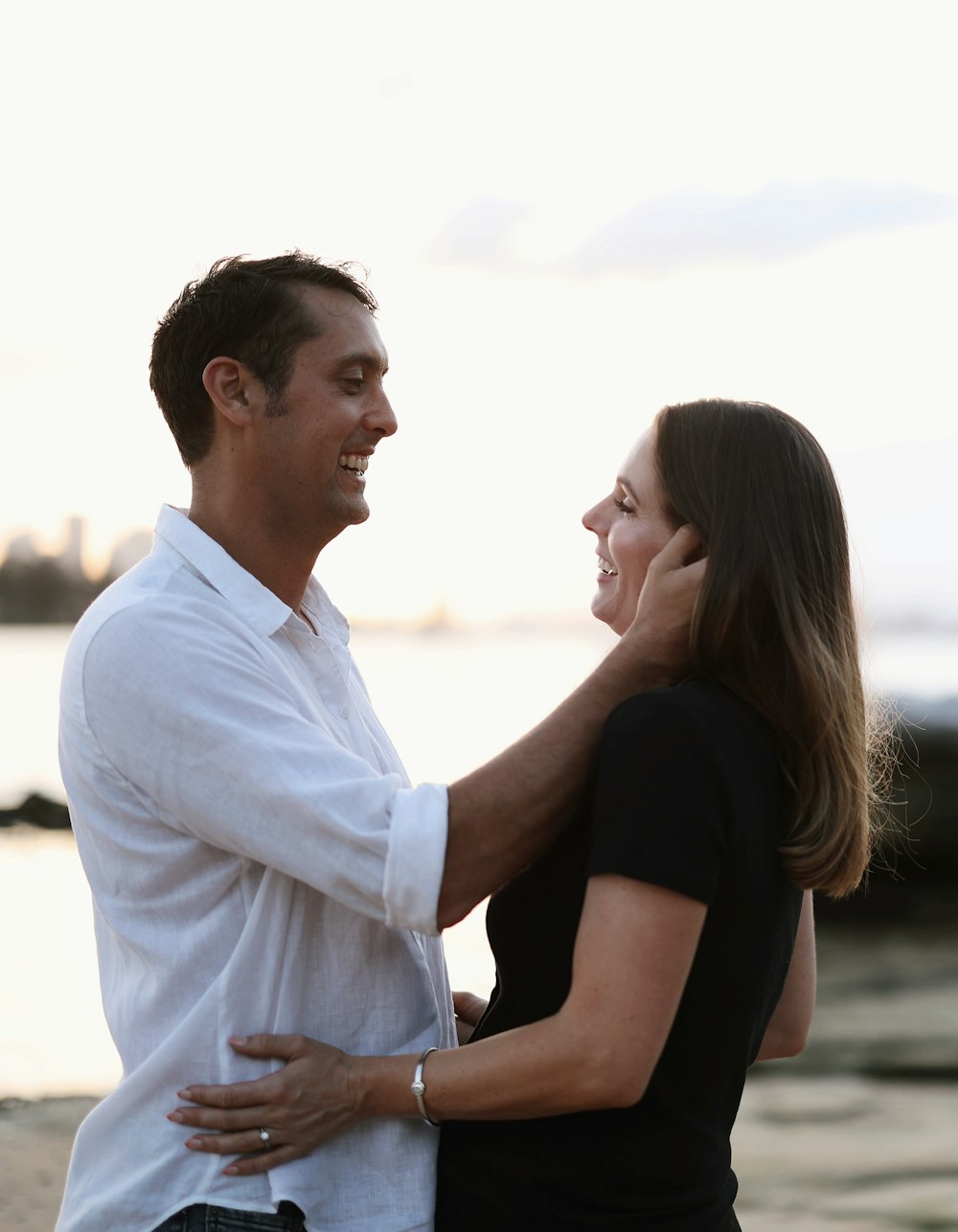 a man and woman standing on a beach next to the ocean