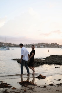 A couple walking hand-in-hand on a pristine white sandy beach at sunset.