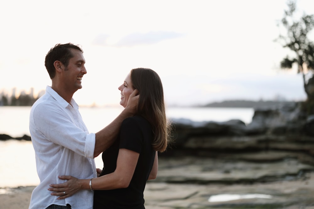 a man and a woman standing next to each other on a beach