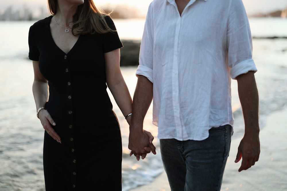 a man and a woman holding hands on the beach