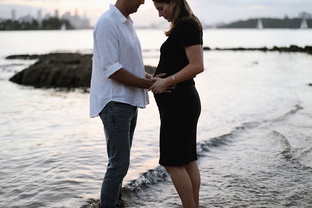 a man and a woman standing on a beach next to a body of water