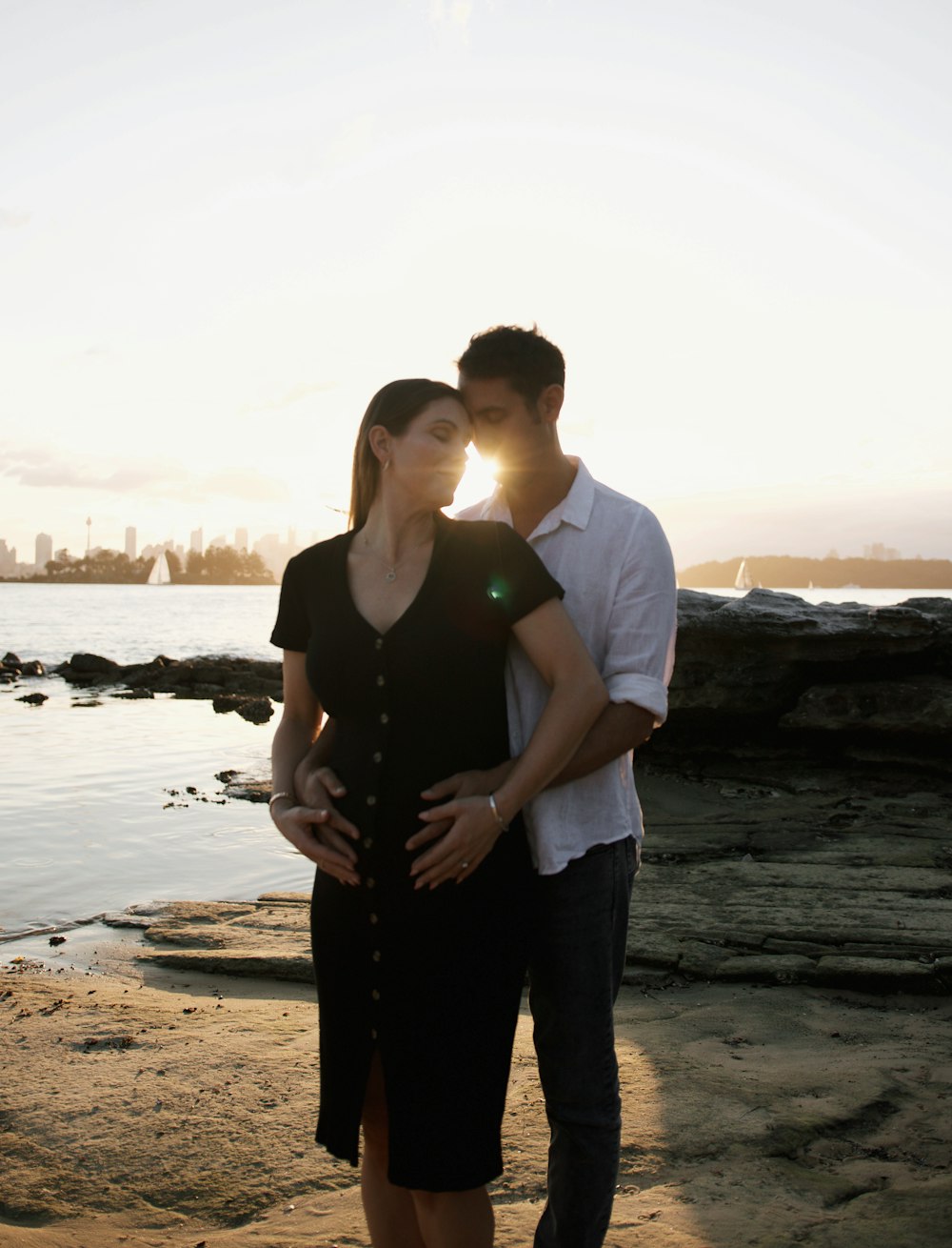 a man and woman standing on a beach next to the ocean