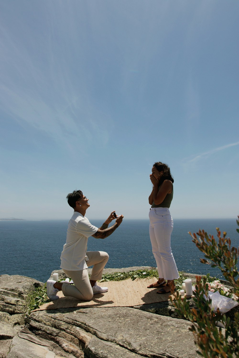 a man kneeling down next to a woman on top of a cliff