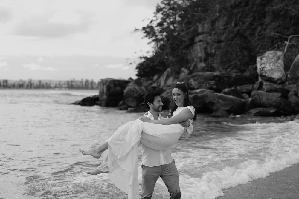 a man carrying a woman on his back on the beach