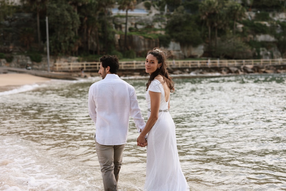 a man and a woman standing on a beach next to the ocean