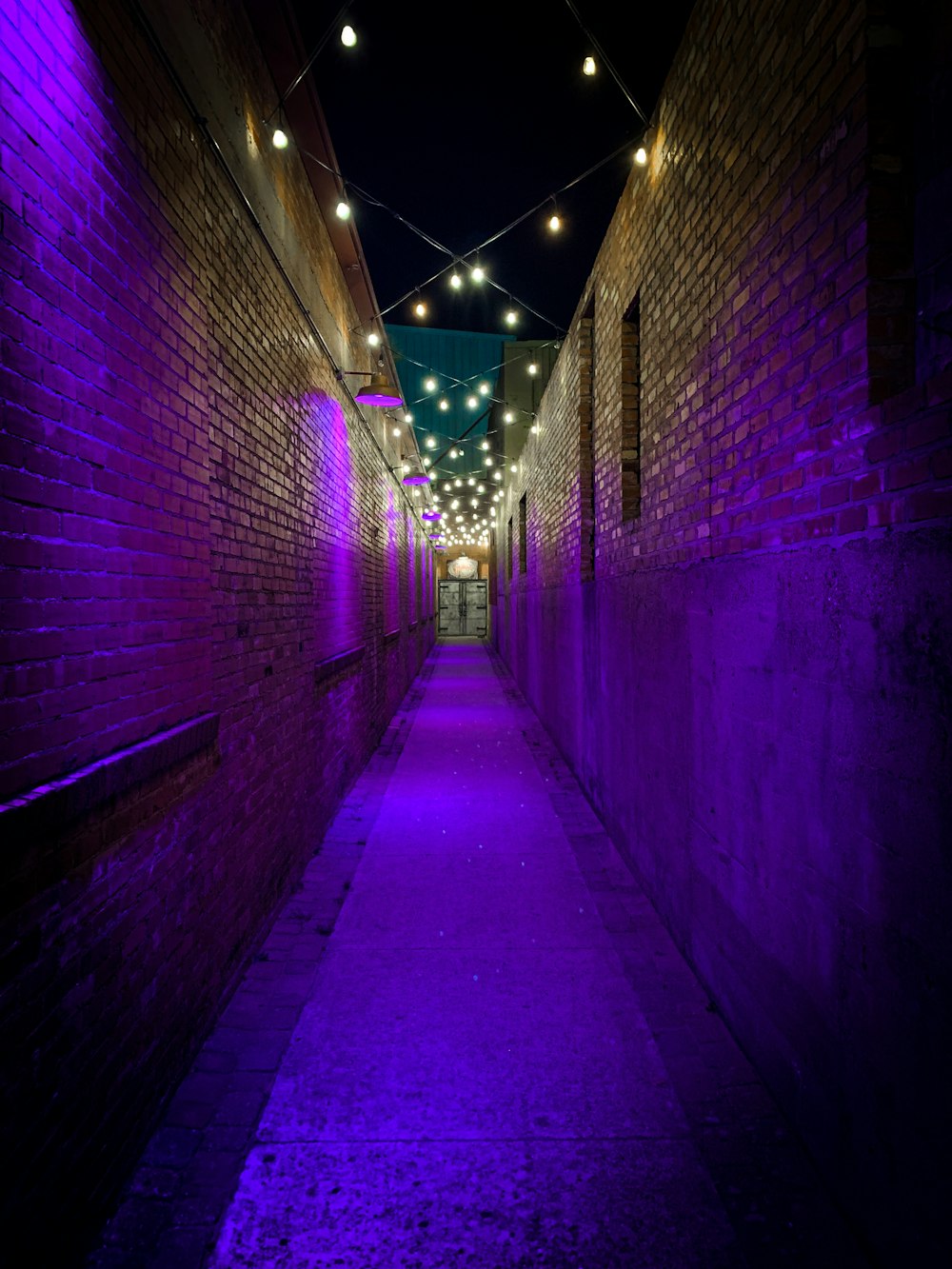 a long narrow alley with purple lights on the walls