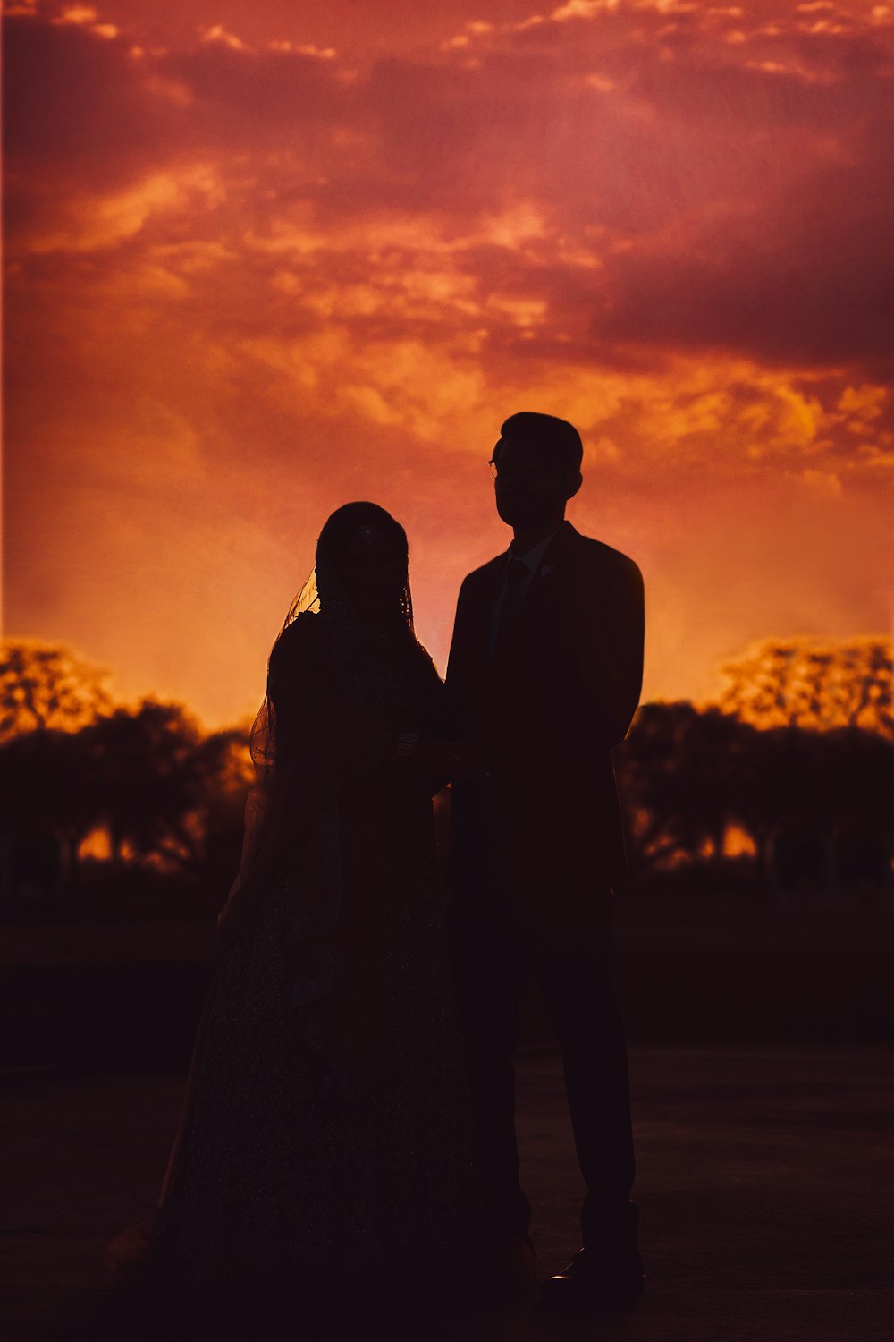 a man and a woman standing in front of a sunset