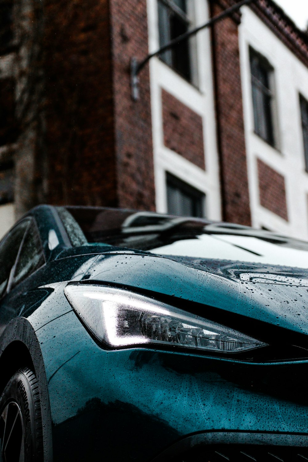 um carro esportivo azul estacionado em frente a um edifício de tijolos