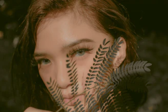 An intimate close-up of a woman’s silhouette framed by matte forest green shadows and crisp parchment highlights.