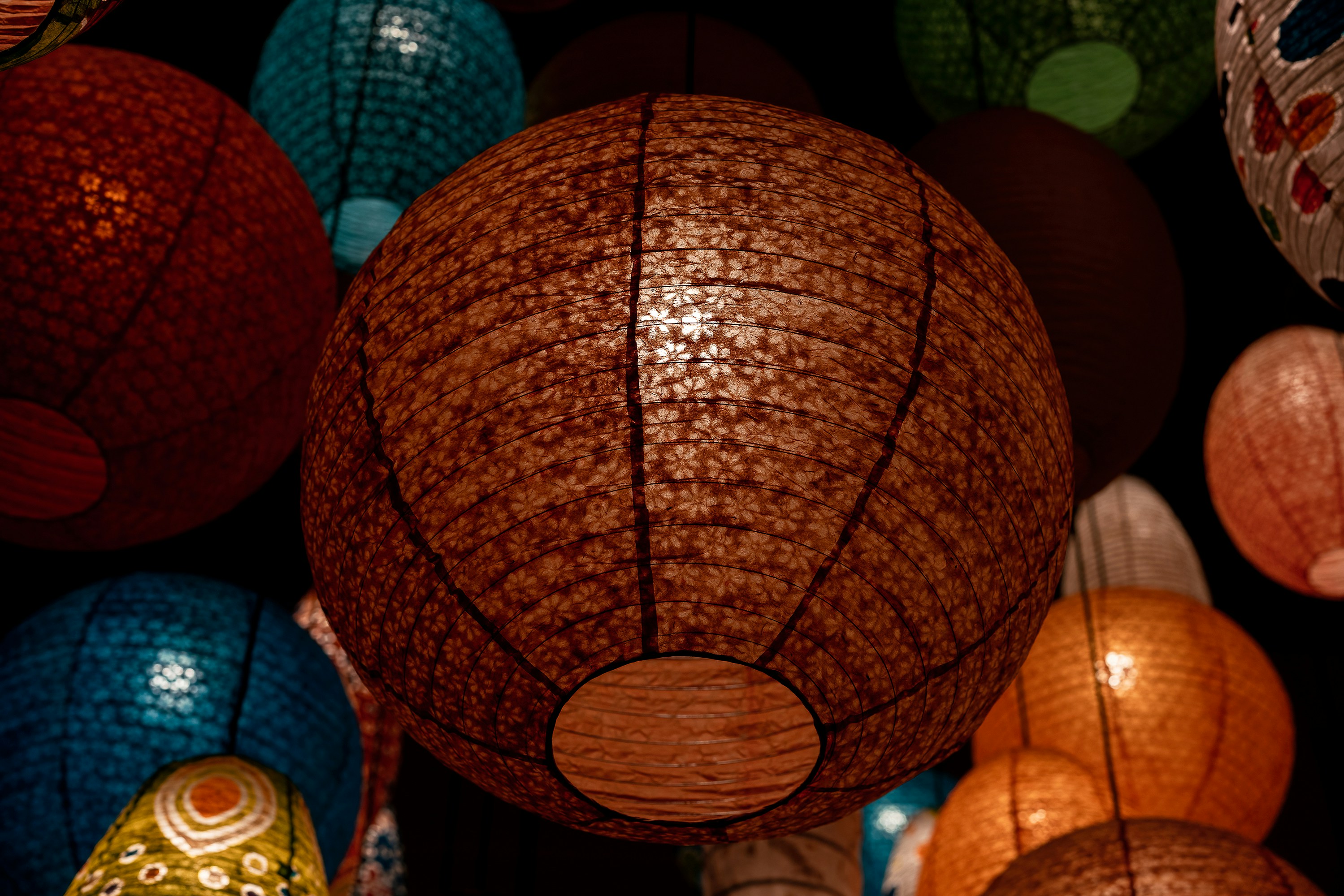 a bunch of different colored lanterns hanging from a ceiling