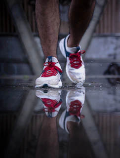 Close-up of a runner's feet pounding the pavement, with black, white, and red shoes reflecting the club's colors.