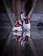 A close-up of a person wearing white running shoes with red and blue accents. The shoes are partially submerged in water, creating a clear reflection on the wet surface.