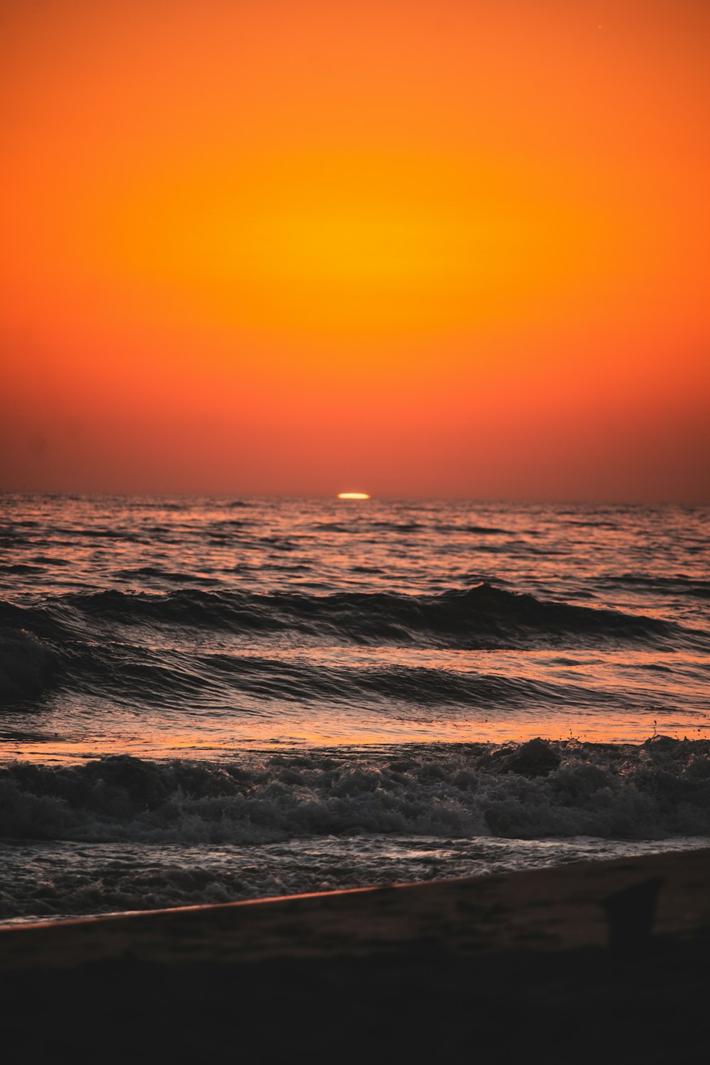 the sun is setting over the ocean with waves