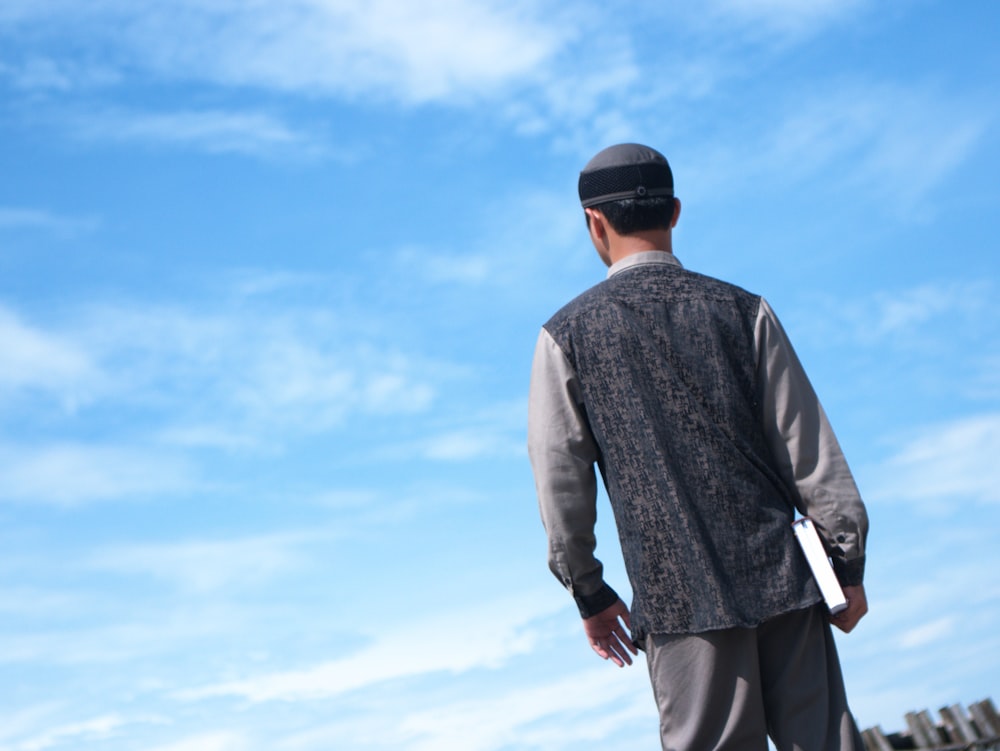 a man standing on top of a skateboard under a blue sky