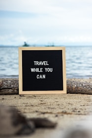 a sign that says travel while you can