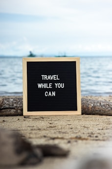 a sign that says travel while you can