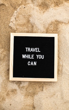 a sign that says travel while you can