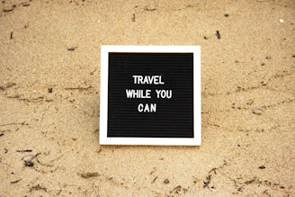 a black and white sign that says travel while you can
