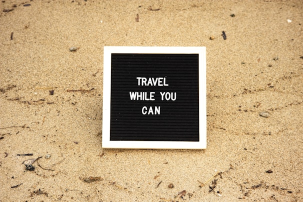 a black and white sign that says travel while you can