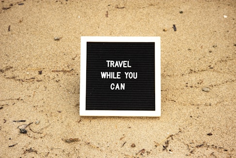 a black and white sign that says travel while you can