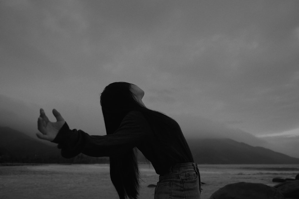 a woman standing on top of a beach next to a body of water