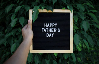 a hand holding a sign that says happy father's day