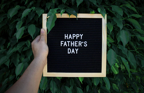 a hand holding a sign that says happy father's day