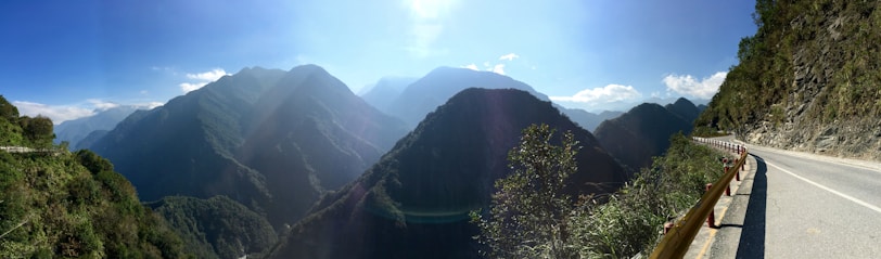 A scenic view of a winding road through lush green mountains under a clear blue sky.