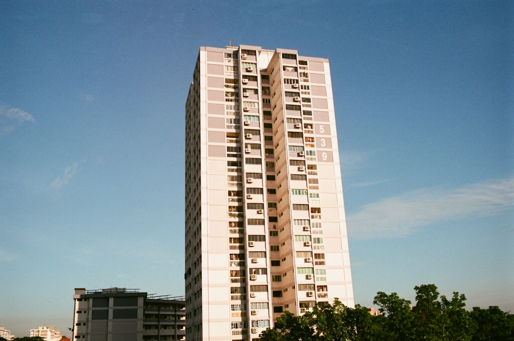 a tall white building sitting next to a lush green park