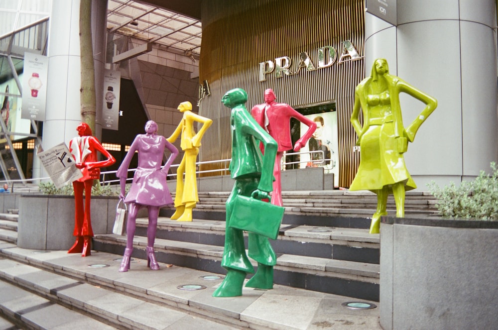 a group of colorfully dressed mannequins on the steps of a building