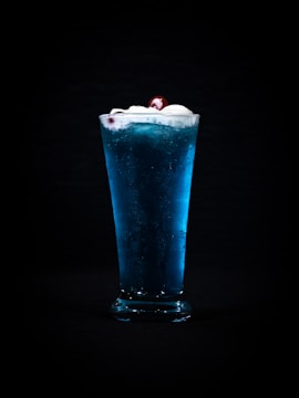 a tall glass filled with ice and a cherry