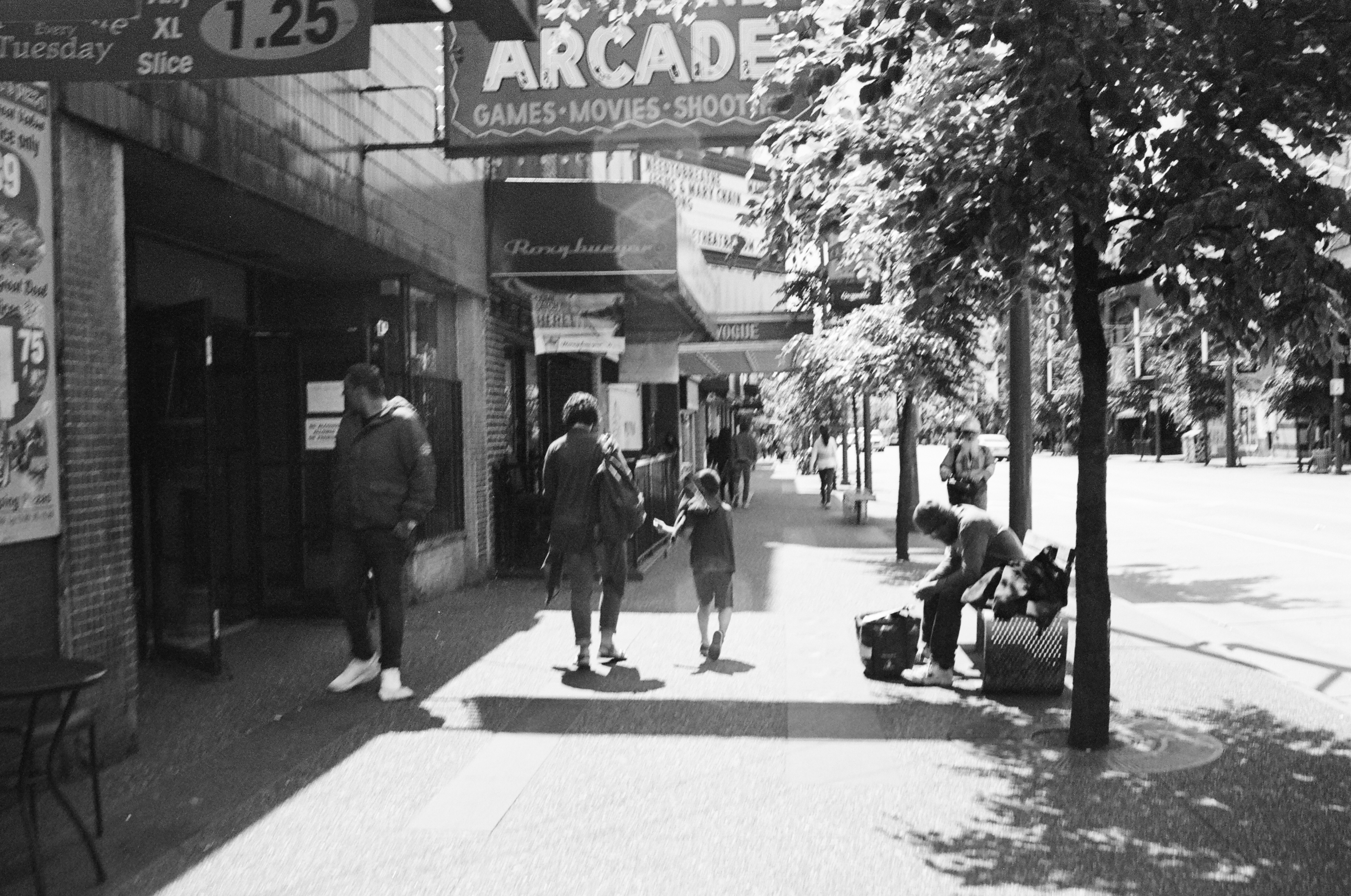 a black and white photo of people walking down a sidewalk