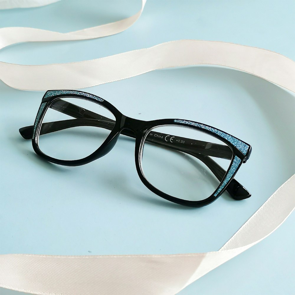 a pair of glasses sitting on top of a white ribbon