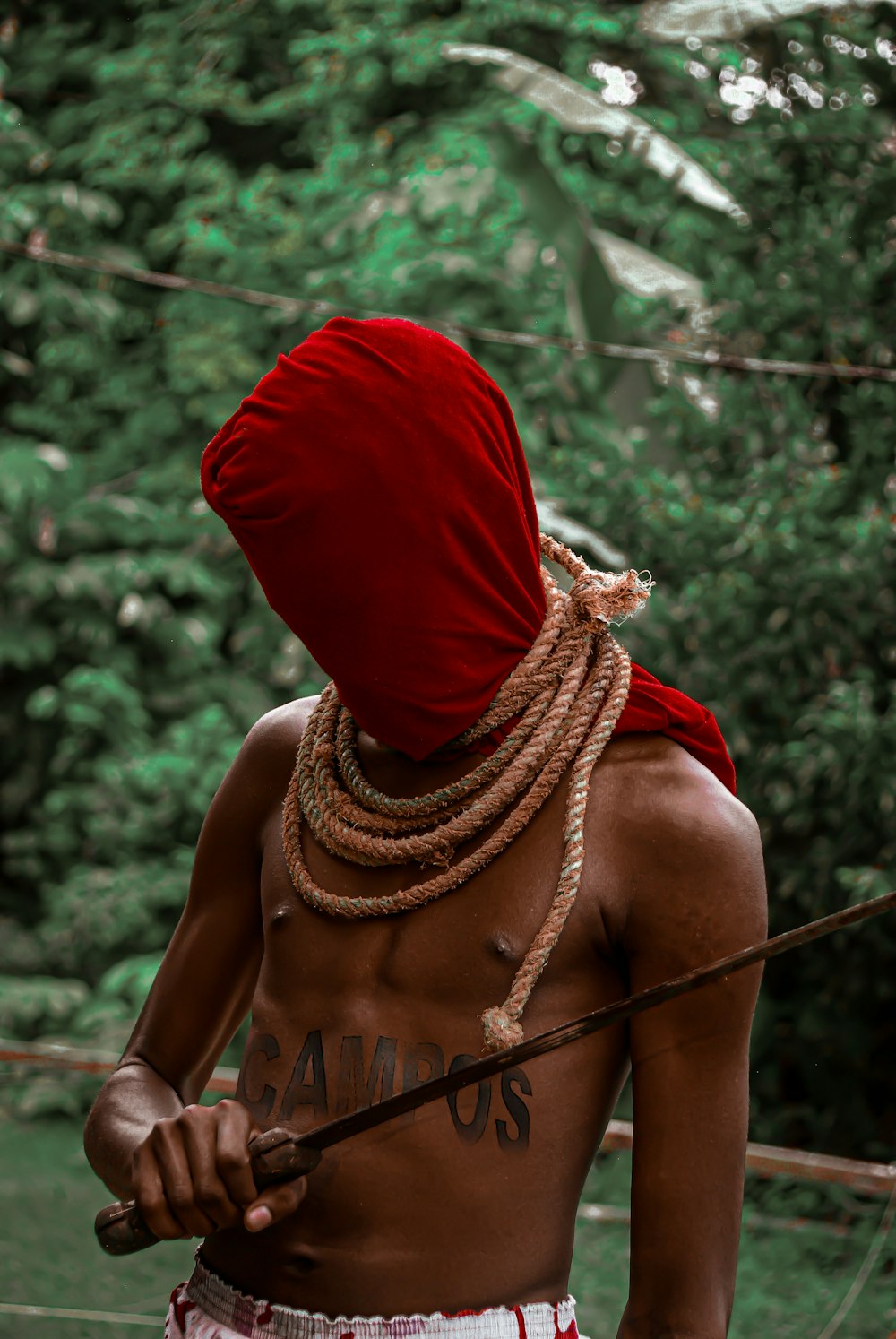a man with a red head covering holding a stick