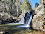 A crystal-clear waterfall cascading into a natural pool surrounded by forest