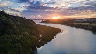 A serene landscape featuring a sunset over a tranquil river, symbolizing the fusion of tradition and modernity.