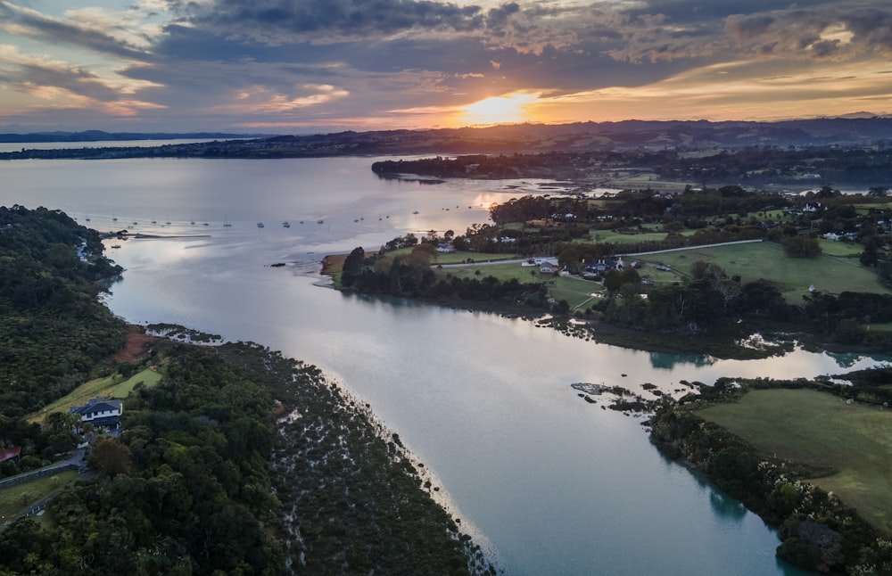 an aerial view of a lake with a sunset in the background