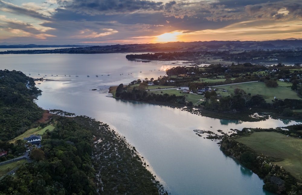 Una vista aérea de un lago con una puesta de sol en el fondo