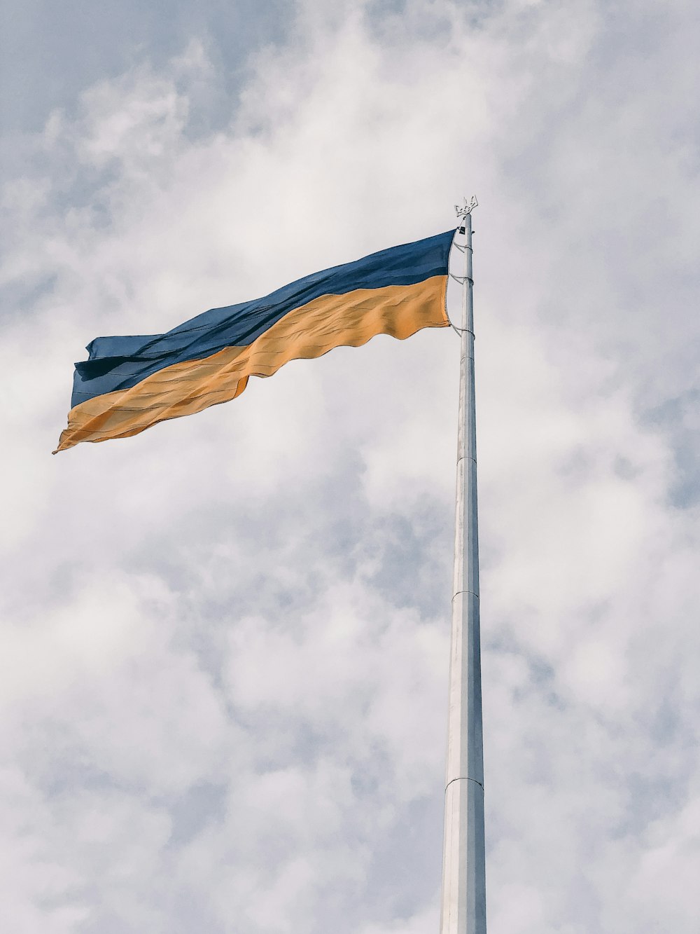 a flag flying high in the sky on a cloudy day