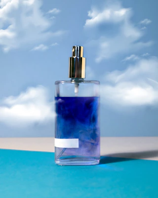 A bright, refreshing spray bottle catching sunlight with a blurred beach background.