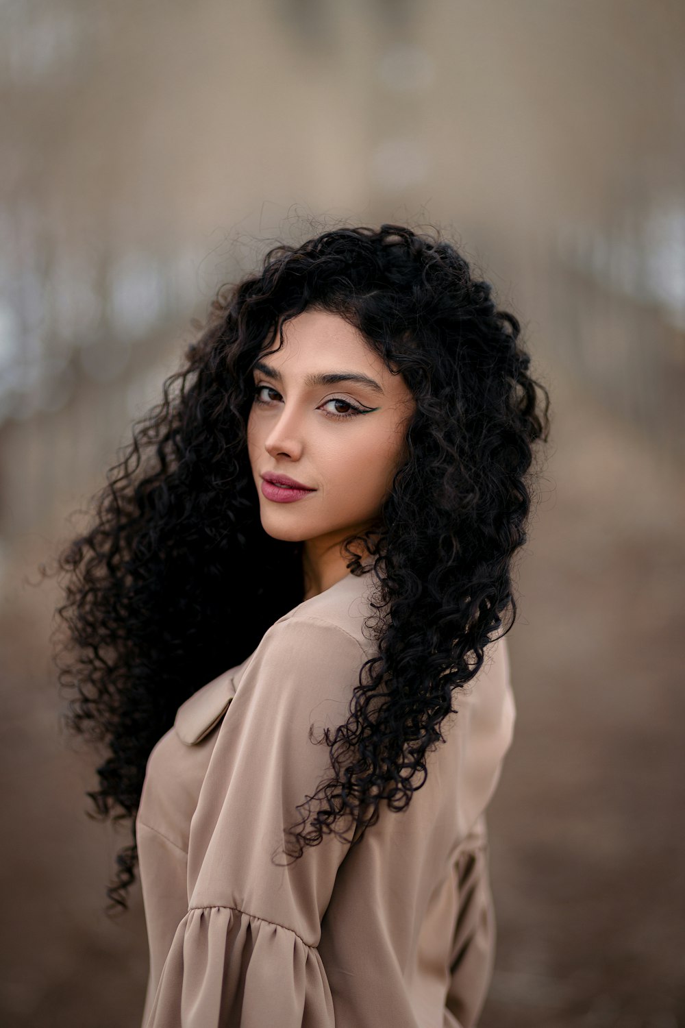 a woman with long black curly hair posing for a picture