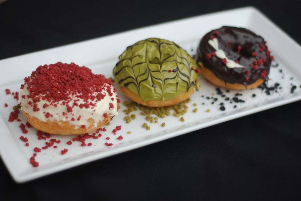 a white plate topped with three donuts covered in frosting