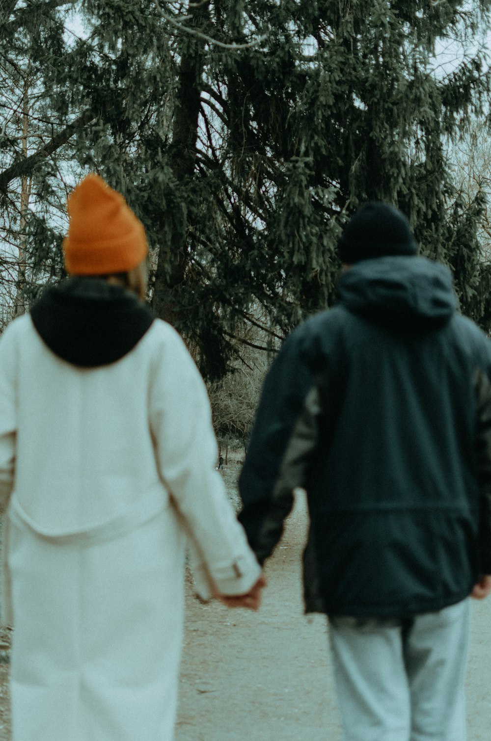 a man and a woman walking down a path holding hands