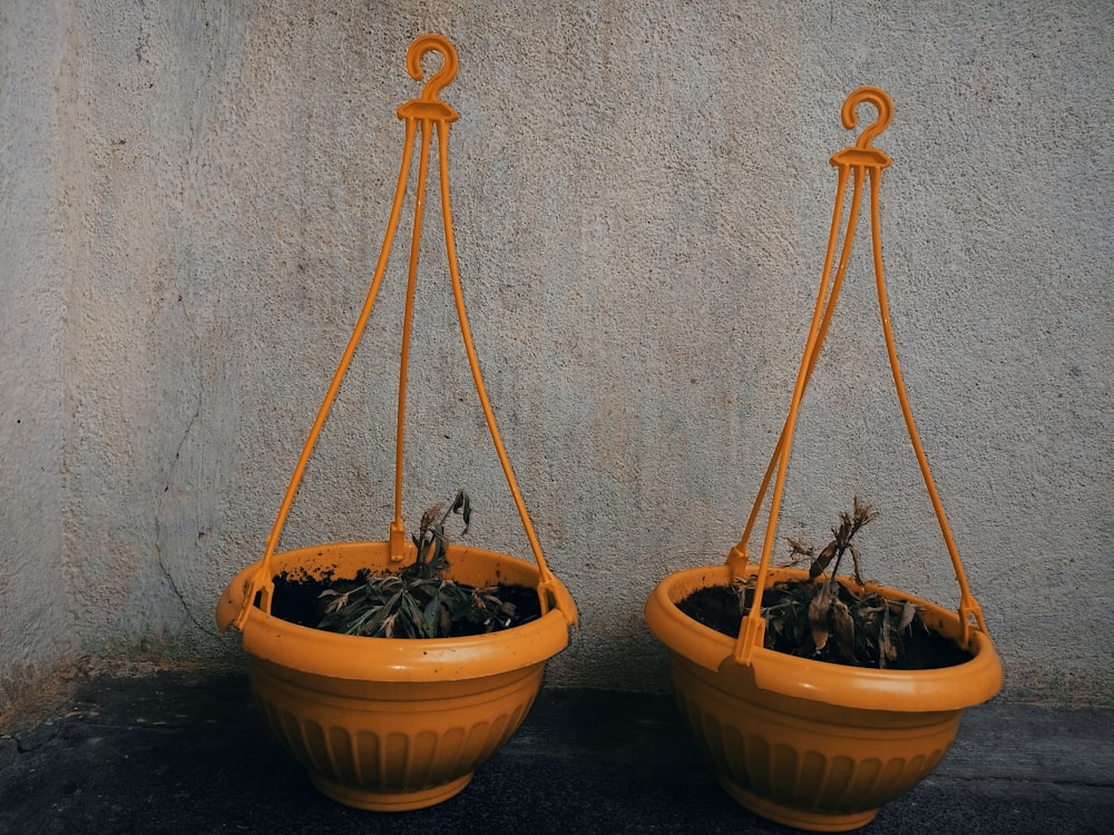 two orange hanging planters with plants in them