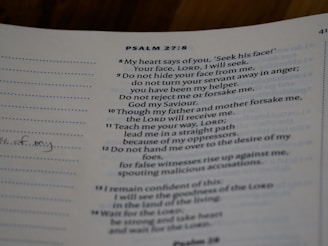 A close-up view of a page from a book with text from Psalm 27:8-14. The text is printed in a neat font on a slightly off-white page. There are sections of dotted lines on the left side and handwritten notes visible on the margin. The text references themes of seeking, guidance, and faith.