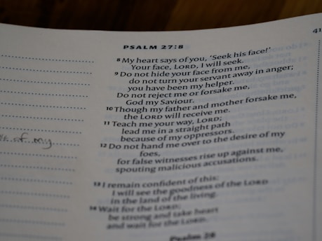 A close-up view of a page from a book with text from Psalm 27:8-14. The text is printed in a neat font on a slightly off-white page. There are sections of dotted lines on the left side and handwritten notes visible on the margin. The text references themes of seeking, guidance, and faith.