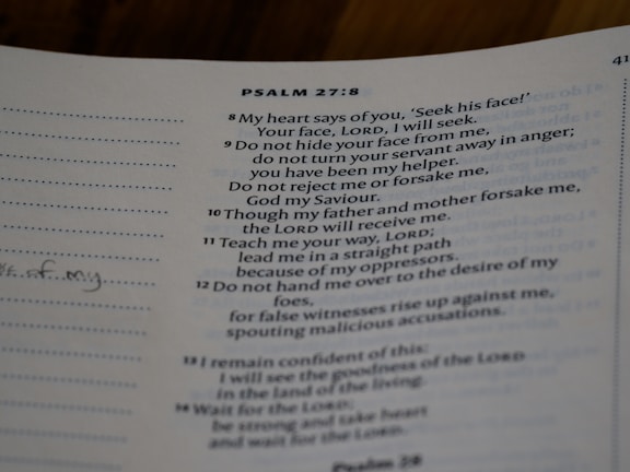A close-up view of a page from a book with text from Psalm 27:8-14. The text is printed in a neat font on a slightly off-white page. There are sections of dotted lines on the left side and handwritten notes visible on the margin. The text references themes of seeking, guidance, and faith.