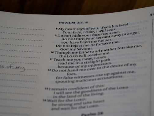 A close-up view of a page from a book with text from Psalm 27:8-14. The text is printed in a neat font on a slightly off-white page. There are sections of dotted lines on the left side and handwritten notes visible on the margin. The text references themes of seeking, guidance, and faith.